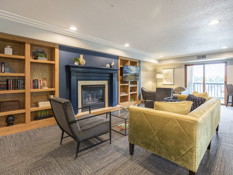 Community room with a variety of seating in front of a fireplace, pillared by bookshelves